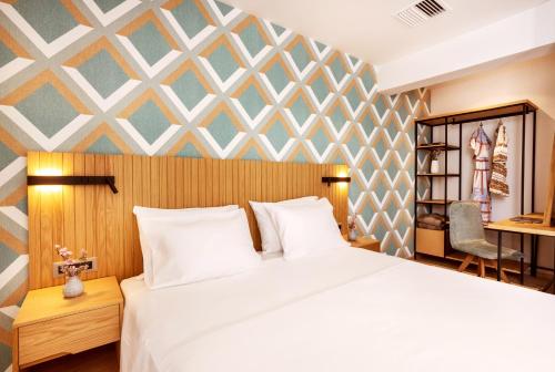 sypialnia z białym łóżkiem i geometryczną ścianą w obiekcie DAYS City Suites Athens w Atenach