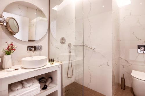 uma casa de banho branca com um chuveiro e um lavatório. em DAYS City Suites Athens em Atenas