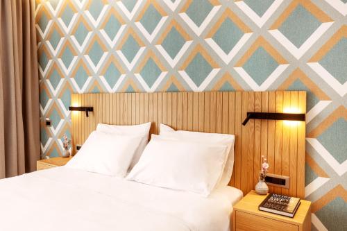 a bedroom with a white bed with a geometric wall at DAYS City Suites Athens in Athens