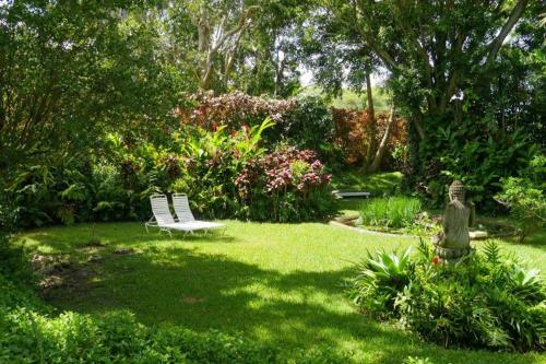a garden with a white bench in the grass at Waterfall House with Ocean Views in Haiku, Maui in Huelo