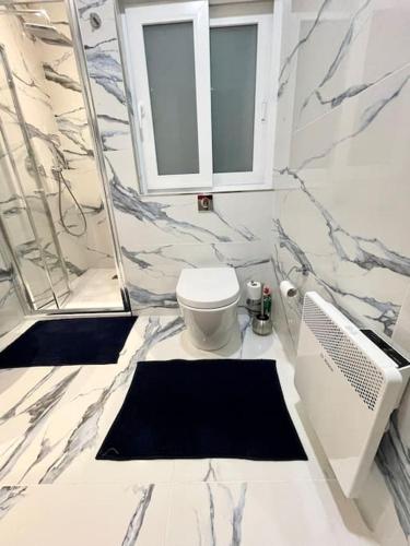 a white bathroom with a toilet and a window at Sunnyside Penthouse in Tarxien