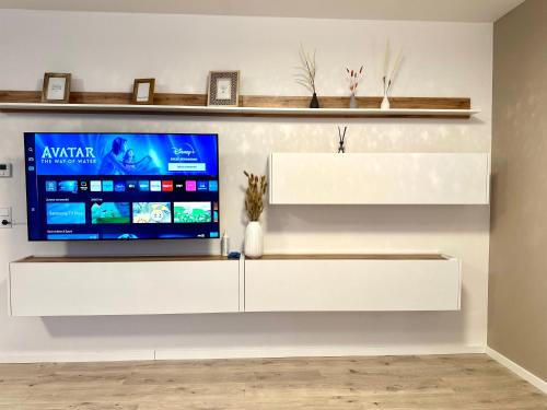 a white entertainment center with a tv on a wall at Mein Apartment, Forest View mit Balkon und Klima, bis 10 Personen in Bad Kreuznach