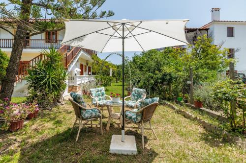 a table with chairs and an umbrella in a yard at Panagou Studios in Skopelos Town