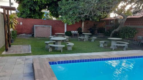 a backyard with picnic tables and a swimming pool at Chalé em Tamandaré in Tamandaré