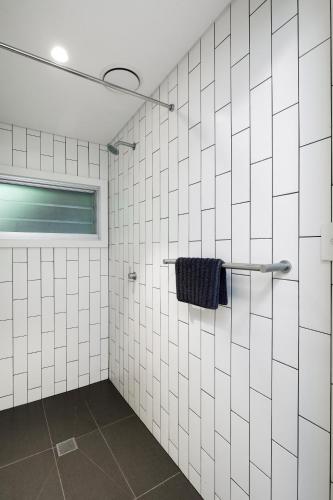 a bathroom with white tiled walls and a towel rack at Currawong Beach Cottages in Great Mackerel Beach