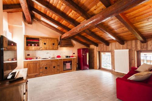 una grande cucina con soffitti in legno e un divano rosso di Emilio Apartments a La Salle