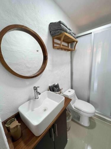 a bathroom with a sink and a toilet and a mirror at Departamento nuevo a estrenar! in Manzanillo