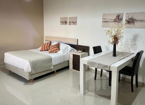 1 dormitorio con cama, escritorio, mesa y silla en Apartamento de las Araucarias, en Esquel