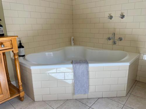a white bath tub in a white tiled bathroom at Barnard street Cottage in Bendigo