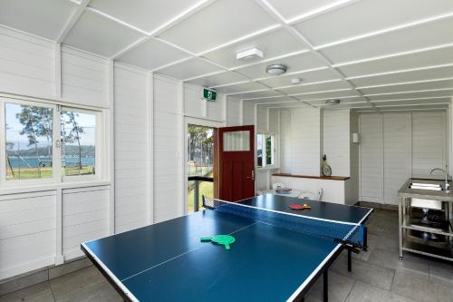 a ping pong table in a room with a ping pong racket at Currawong Beach Cottages in Great Mackerel Beach