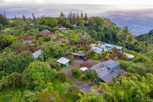 an aerial view of a house on a hill next to the ocean at Jasmine Suite on Lush farm in Haiku, Maui jungle in Huelo
