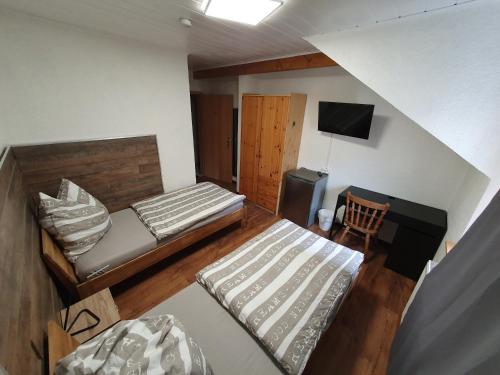 Habitación pequeña con 2 camas y TV. en Hotel Restaurant TAPASTA, en Neuwied