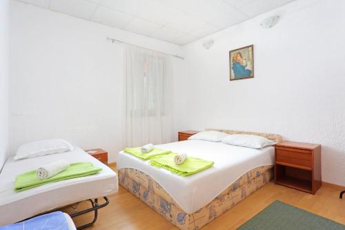 een slaapkamer met 2 bedden en groene handdoeken bij Apartments by the sea Orij, Omis - 7534 in Dugi Rat