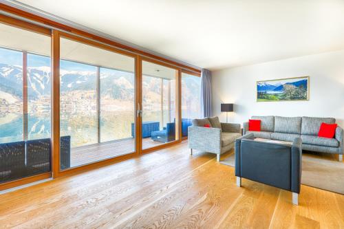 a living room with a couch and chairs and windows at Residence Bellevue - incl Summercard in Zell am See