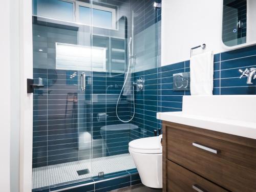 a blue tiled bathroom with a shower and a toilet at The Redline Venice in Los Angeles
