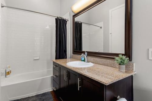 uma casa de banho com um lavatório e um espelho grande em The Olivia: Riverwalk Loft em San Antonio