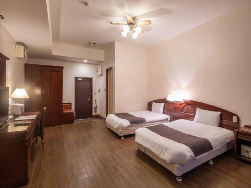 Habitación de hotel con 2 camas y ventilador de techo. en Hotel La Teada Iriomote, en Iriomote