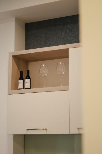 two wine glasses and wine bottles on a shelf at Rooftop Apart-Hotel in Yerevan