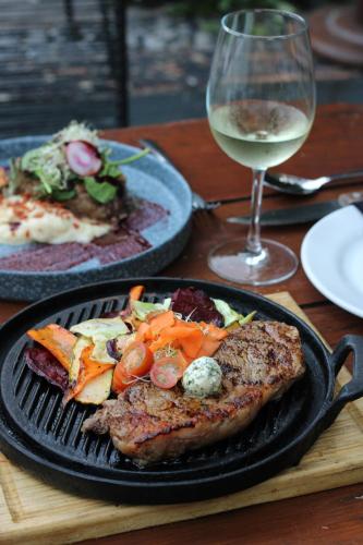 a pan with meat and vegetables on a table with a glass of wine at Piedra de Agua Merida in Mérida