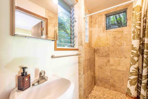 La salle de bains est pourvue d'un lavabo et d'une douche. dans l'établissement Plumeria Room on a Lush Farm on Maui's North Shore, à Huelo
