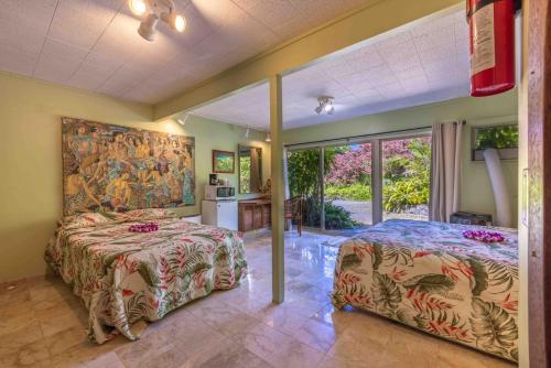 a bedroom with two beds and a painting on the wall at Plumeria Room on a Lush Farm on Maui's North Shore in Huelo