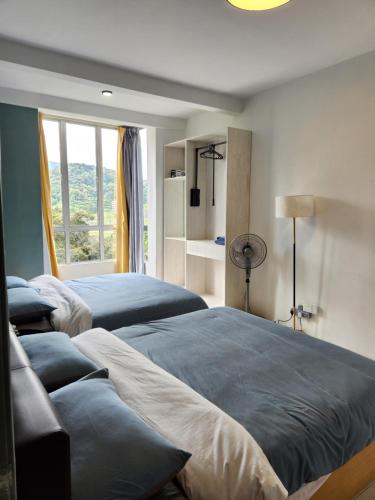 a bedroom with two beds and a window at The Art Gallery Emerald Avenue Cameron Highlands 10Pax 828 Wifi in Brinchang