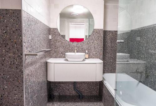 a bathroom with a sink and a mirror and a tub at Modern Boutique CBD 2BR 1st Floor Apt in Canberra