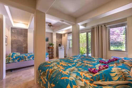 a bedroom with a large bed with a colorful blanket at Gardenia Room on Tropical Lush Farm in Haiku, Maui in Huelo
