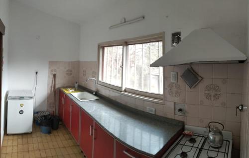 cocina con armarios rojos, fregadero y ventana en Casa/ Villa General Belgrano en Villa General Belgrano