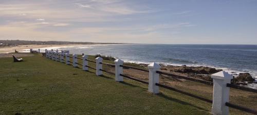 a white fence next to a beach with the ocean at Posada IRSIS in La Pedrera