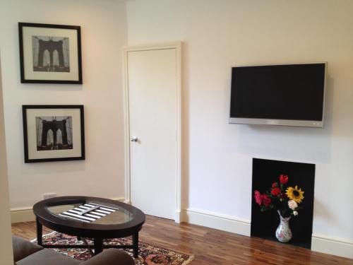 a living room with a television and a vase of flowers at Caledonian Apartments in Edinburgh