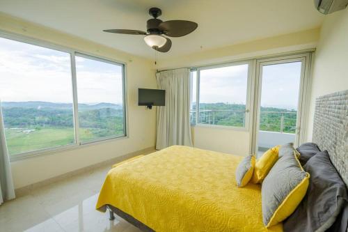 a bedroom with a bed with a ceiling fan and windows at 23o Penthouse Stunning Oceanview Resort Lifestyle in ArraijÃ¡n