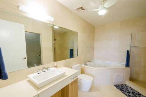 a bathroom with a sink and a toilet and a mirror at 23o Penthouse Stunning Oceanview Resort Lifestyle in ArraijÃ¡n