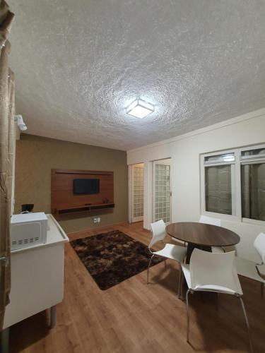 ein Wohnzimmer mit einem Tisch und weißen Stühlen in der Unterkunft Villa Ida Acomodações, 3 suítes aconchegantes e charmosas no centro in Serra Negra