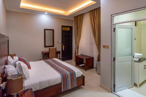 a hotel room with a bed and a bathroom at Las Vegas Garden Hotel Mbarara in Mbarara