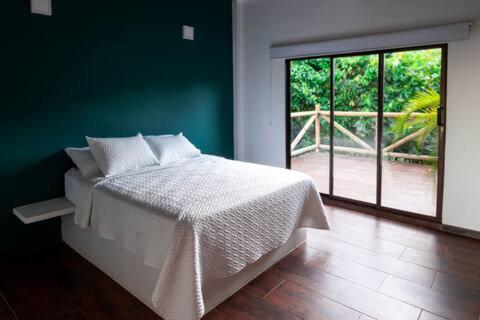 1 dormitorio con cama blanca y ventana grande en Minka Paradise, en Minca