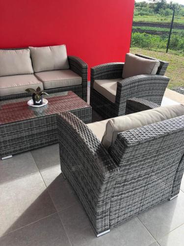 eine Terrasse mit Korbstühlen und einem Sofa in der Unterkunft Villa rubis in Saint-François