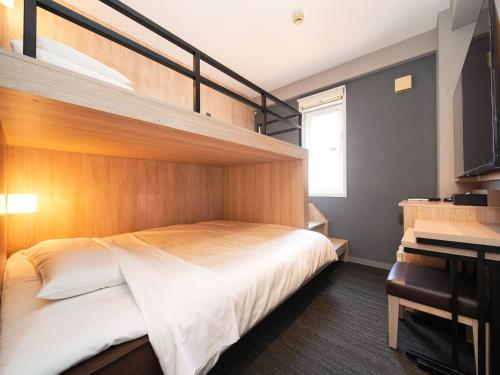 a bedroom with a bunk bed and a desk at Super Hotel Hiroshima in Hiroshima