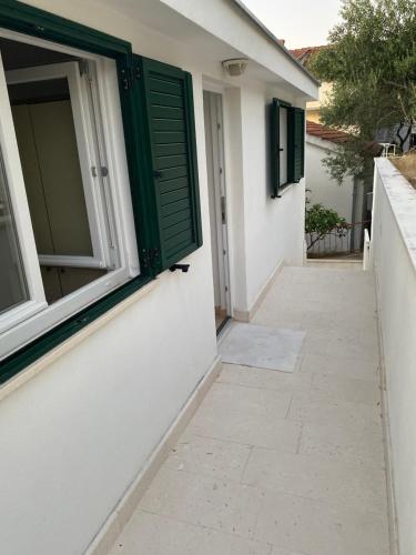 a house with a green window and a walkway at Beachside 2-Bed Bliss! in Blace