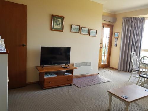 a living room with a flat screen tv and a table at Cornwall Cottage in Cambridge