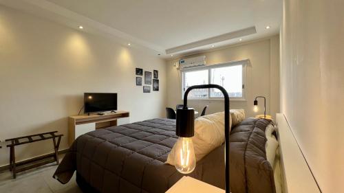 Selbard Suite في بوينس آيرس: غرفة نوم صغيرة بها سرير وتلفزيون