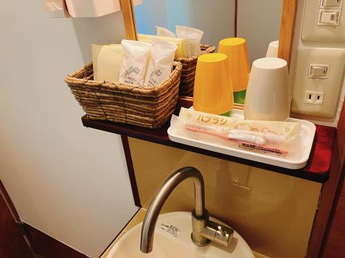 um lavatório de casa de banho com duas cestas de artigos de higiene numa prateleira em YUPOPPO Hakone em Hakone