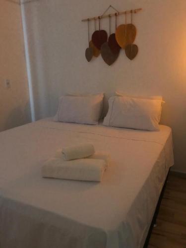 a white bed with two folded towels on it at Quarto Dani in Jericoacoara