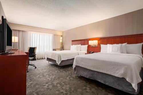 a hotel room with two beds and a flat screen tv at Courtyard by Marriott Springfield in Springfield