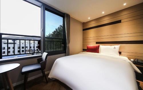 a bedroom with a bed and a desk and a window at Maron Hotel Nampo in Busan