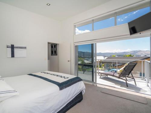 a bedroom with a bed and a sliding glass door at Aquila Waters - Whitianga Holiday Home in Whitianga