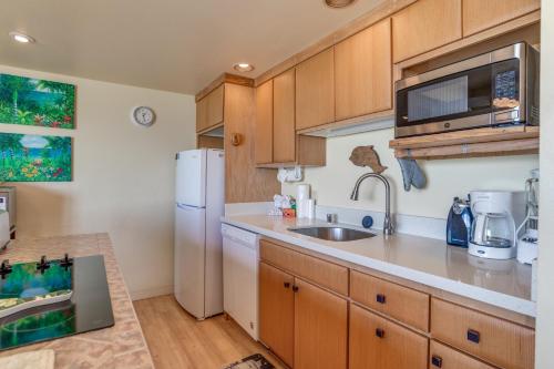 a kitchen with a white refrigerator and a sink at Maui Sands #5G in Kahana