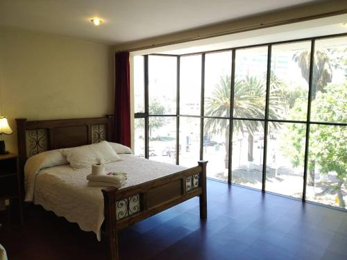 Hotel Maison Fiori Prado في كوتشابامبا: غرفة نوم بسرير ونافذة كبيرة