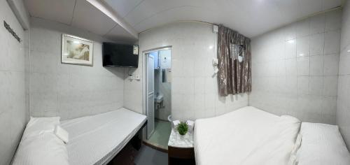 Mandarin Guest House في هونغ كونغ: غرفة صغيرة بسريرين وتلفزيون