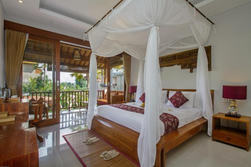 a bedroom with a canopy bed and a balcony at The Runik Ubud in Ubud